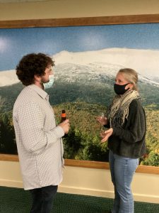 Two people wearing masks chatting over drinks