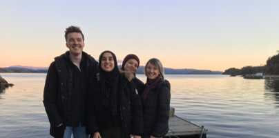 Four people posing for the camera on a jetty at sunset