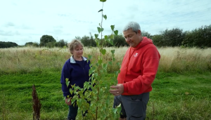 Claire Moulton and Woodland Trust employee standing next to a tree