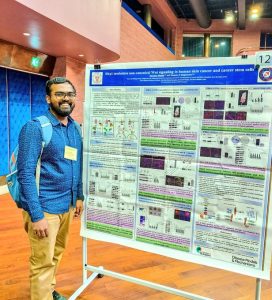 Darshan Mehta attending the Gordon Research Conference, posing for a photograph next to his research poster