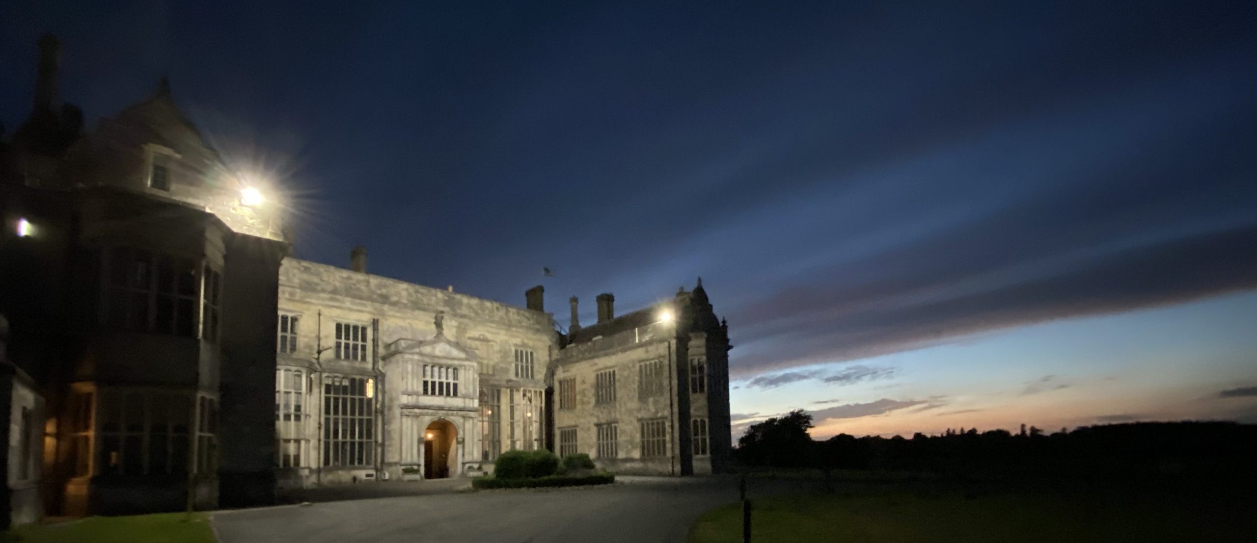 A stately home at dusk, with dramatic cloud formations overhead. 
