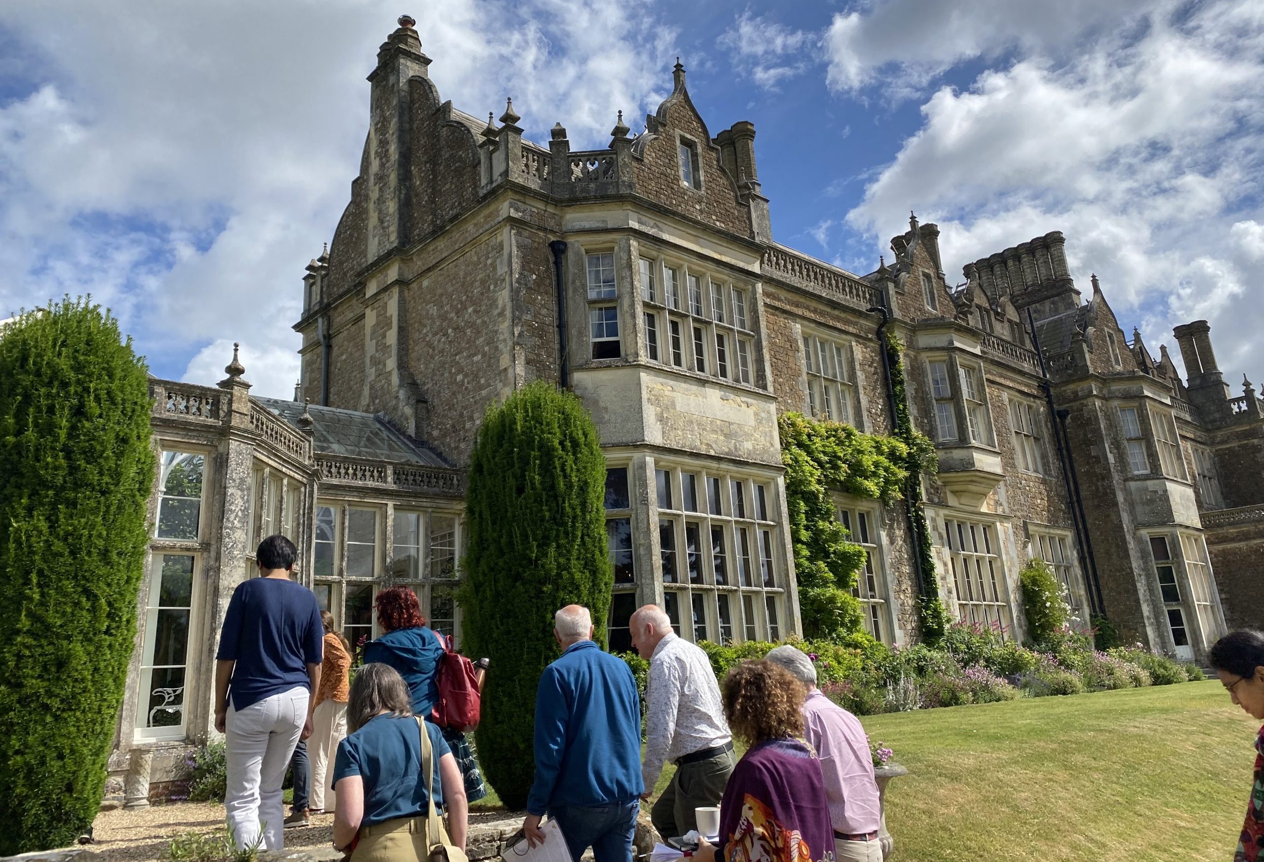 A group of people walking up the steps to a stately home