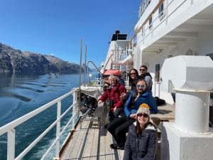 Five people sitting along the side of a research ship