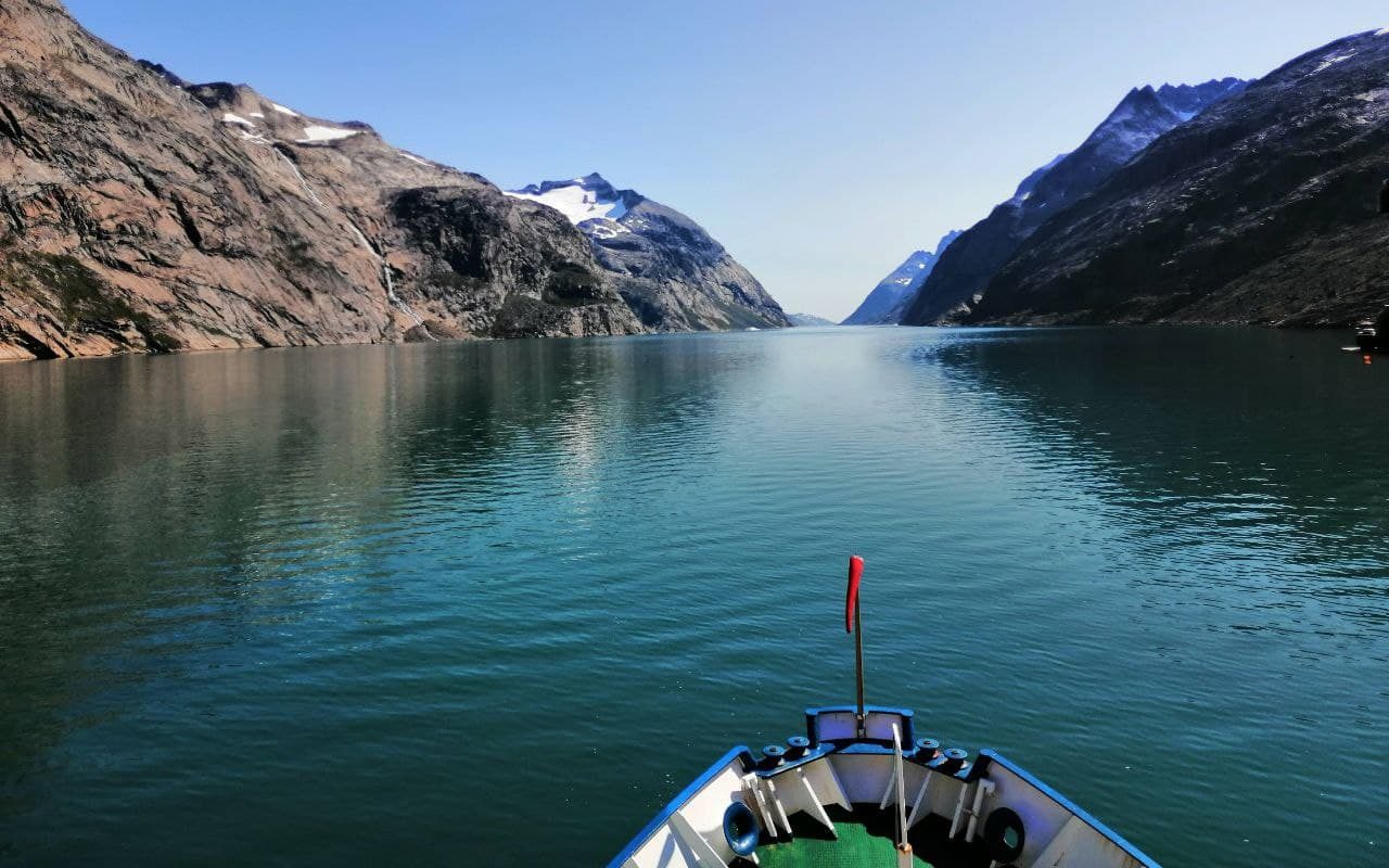The prow of a boat moving through a fjord