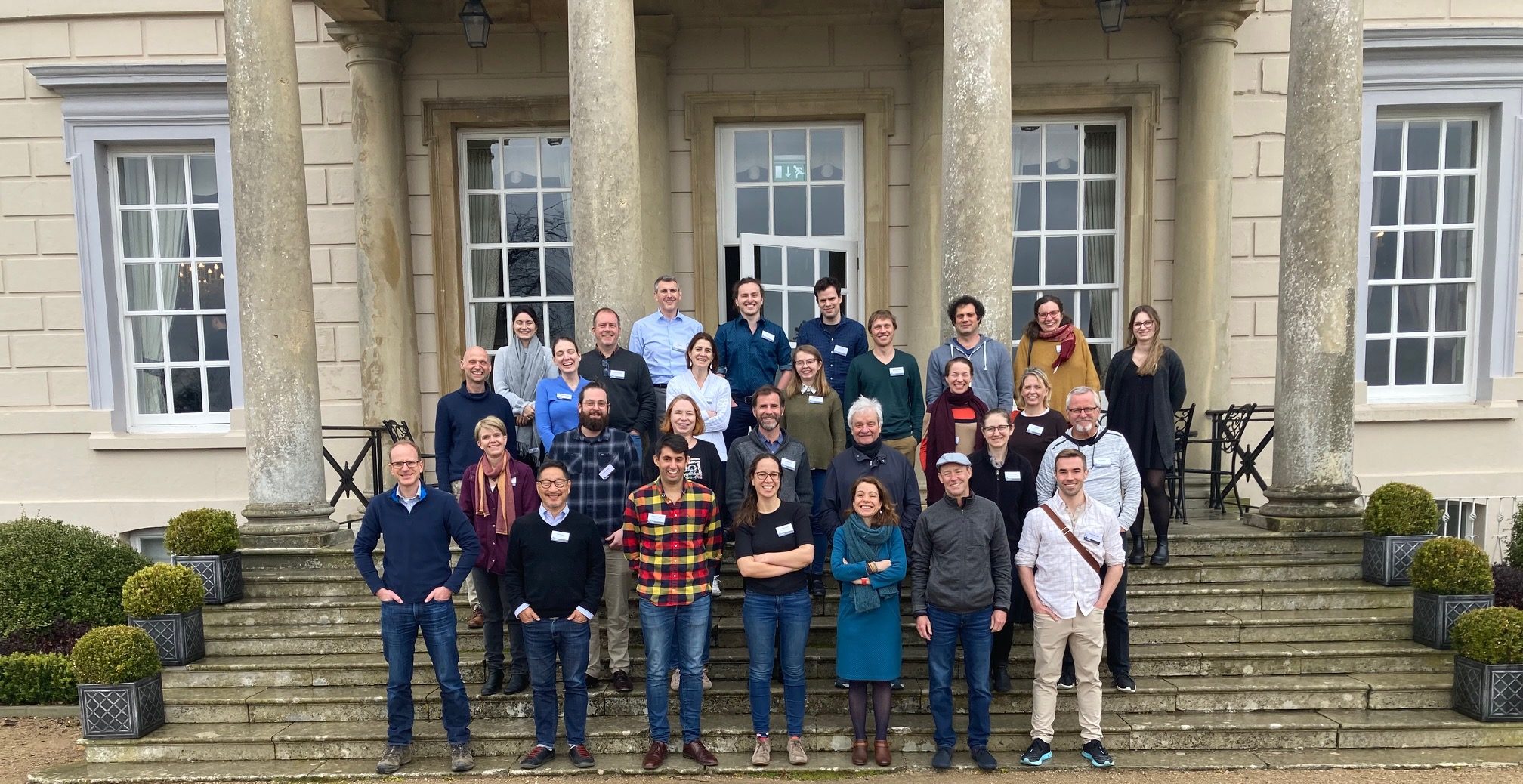 A large group of people posing for a photo on the steps of an old house