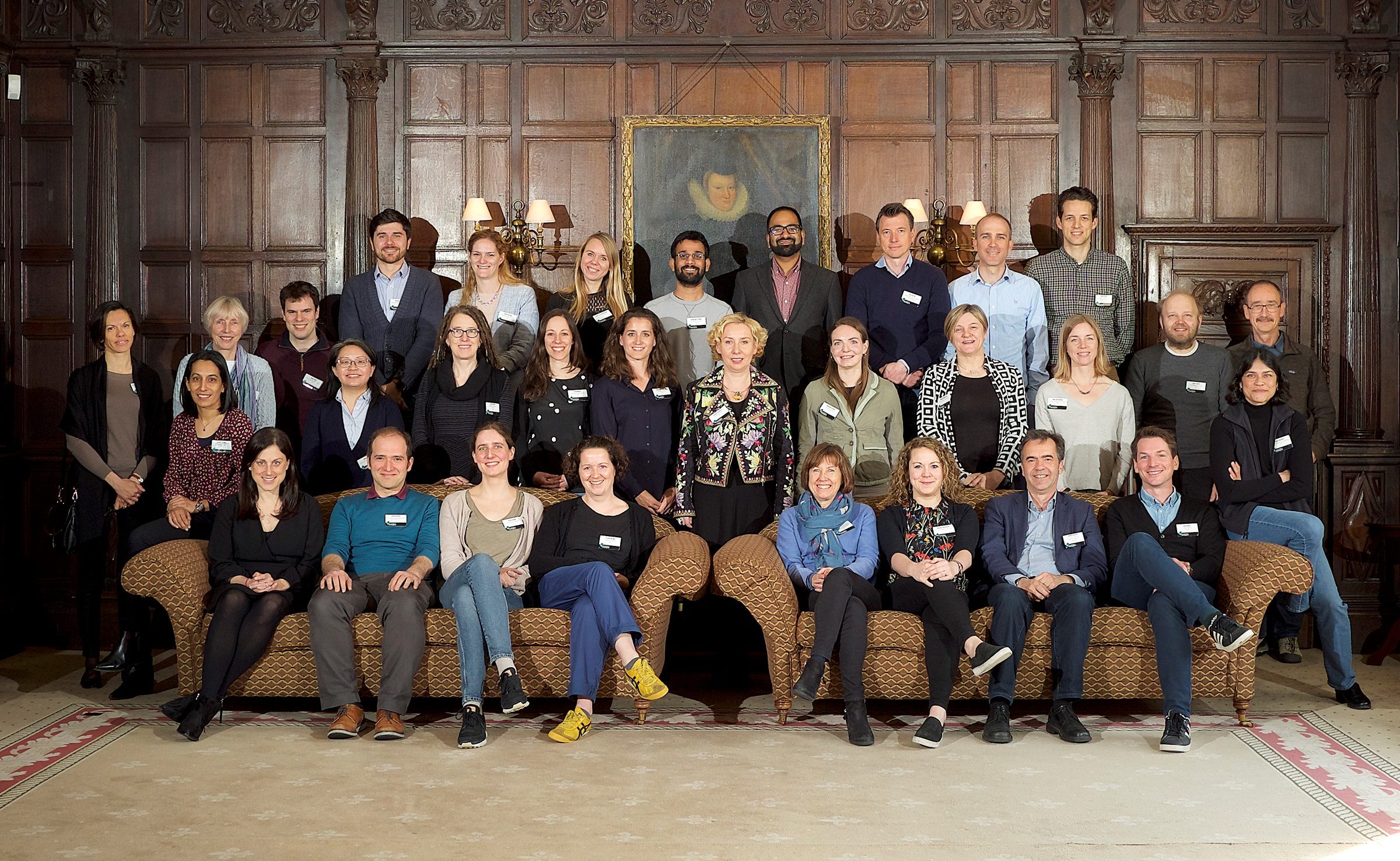 A large group of people seated for a photograph in a wood-panelled room