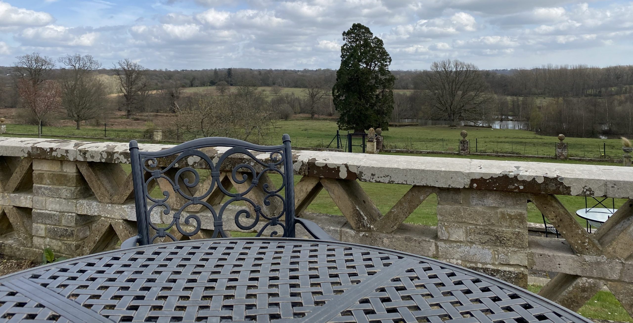 A view of a hilly landscape with a table and chairs in the foreground