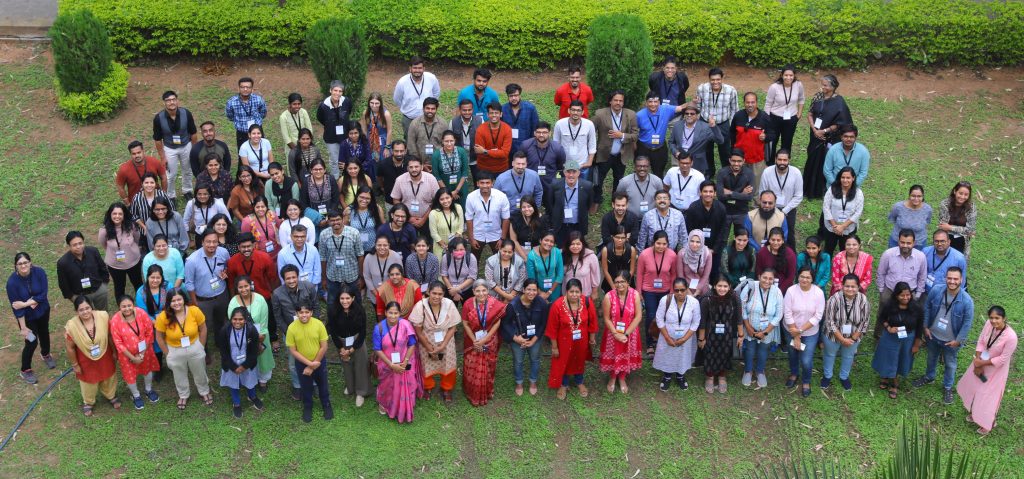 A group of meeting attendees looking up at the camera from the lawn outside the conference venue.