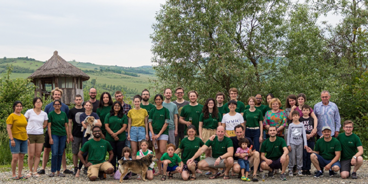 A group of summer school attendees posing for a group photo, with a backdrop of rolling hills.
