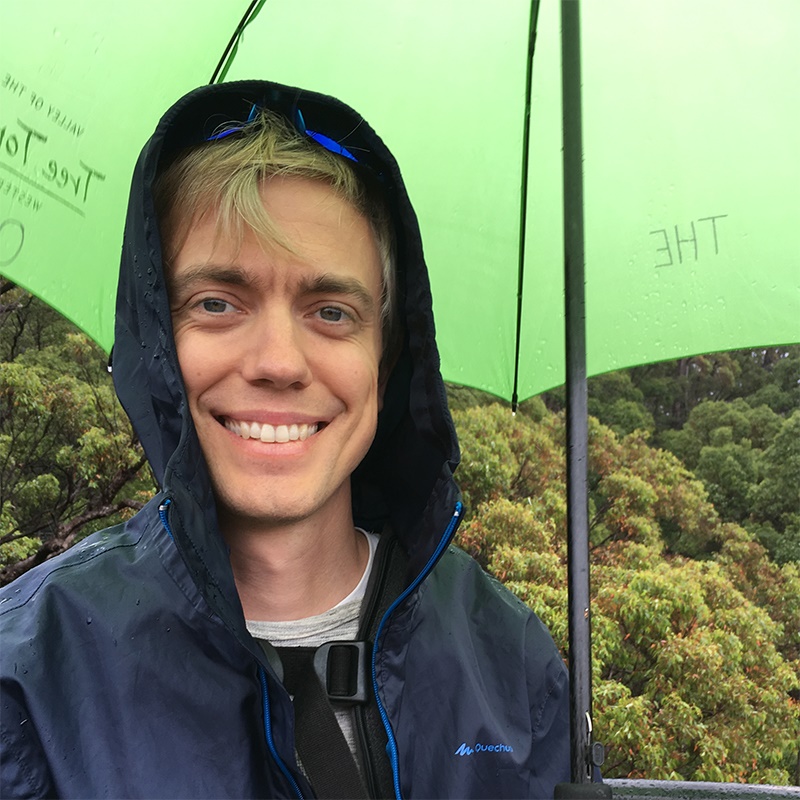 Steven Kelly under an umbrella with trees in the background