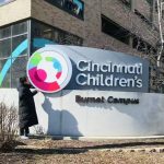Zehuan in front of the entrance sign for Cincinnati Children’s Burnet Campus