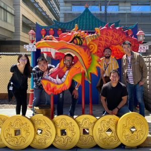 Keying and colleagues posing for a picture in the sunshine in front of an ornamental statue